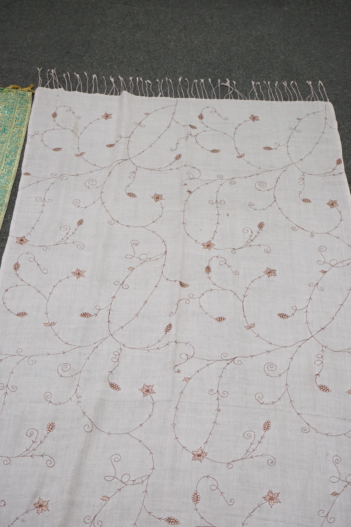 An Indian green and gold silk hand woven brocade stole, a cream pashmina embroidered stole and a similar finely woven and embroidered lilac stole (3). Brocade stole 38cm x 180cm., Condition - light stain to finely woven